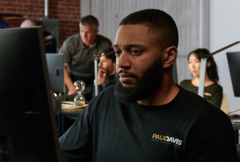 Male Paul Davis Restoration staff member working on the computer to help customer